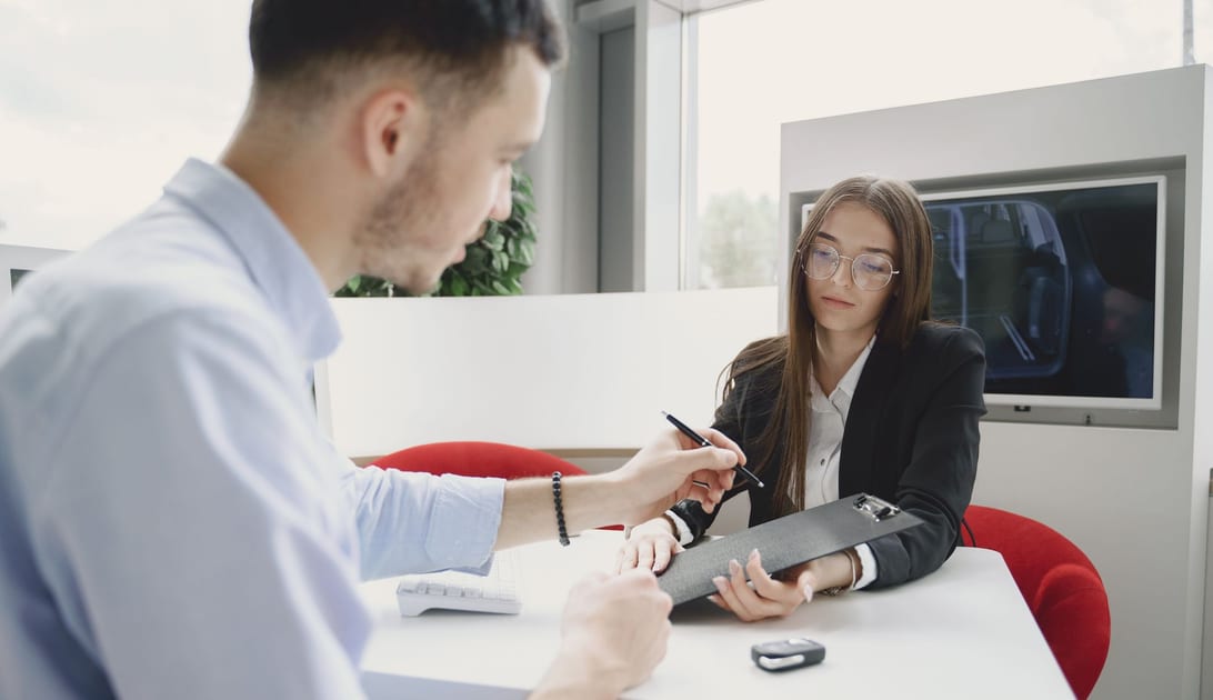 Cliente assinando o contrato de locação com o atendente no balcão da locadora